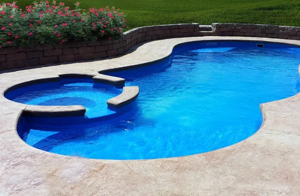 Kidney-shaped pool with attached spa and vivid blue finish