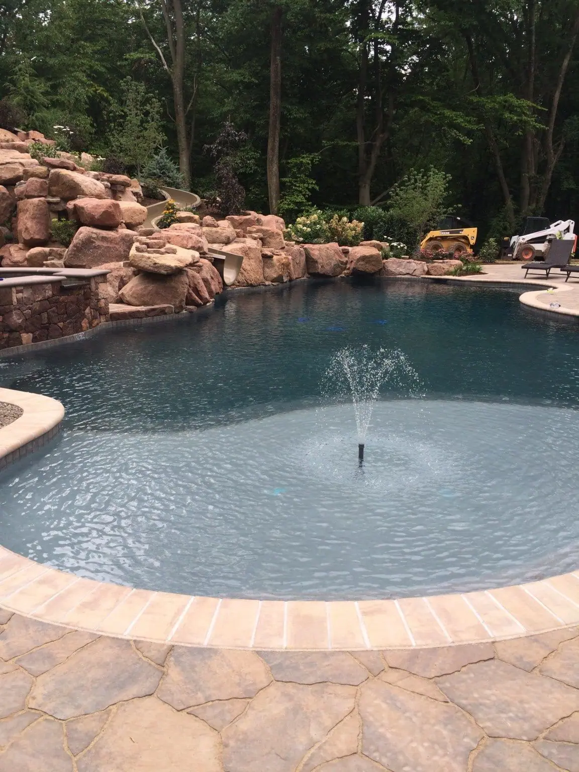 Dark gray pool finish with a center fountain and rock waterfall