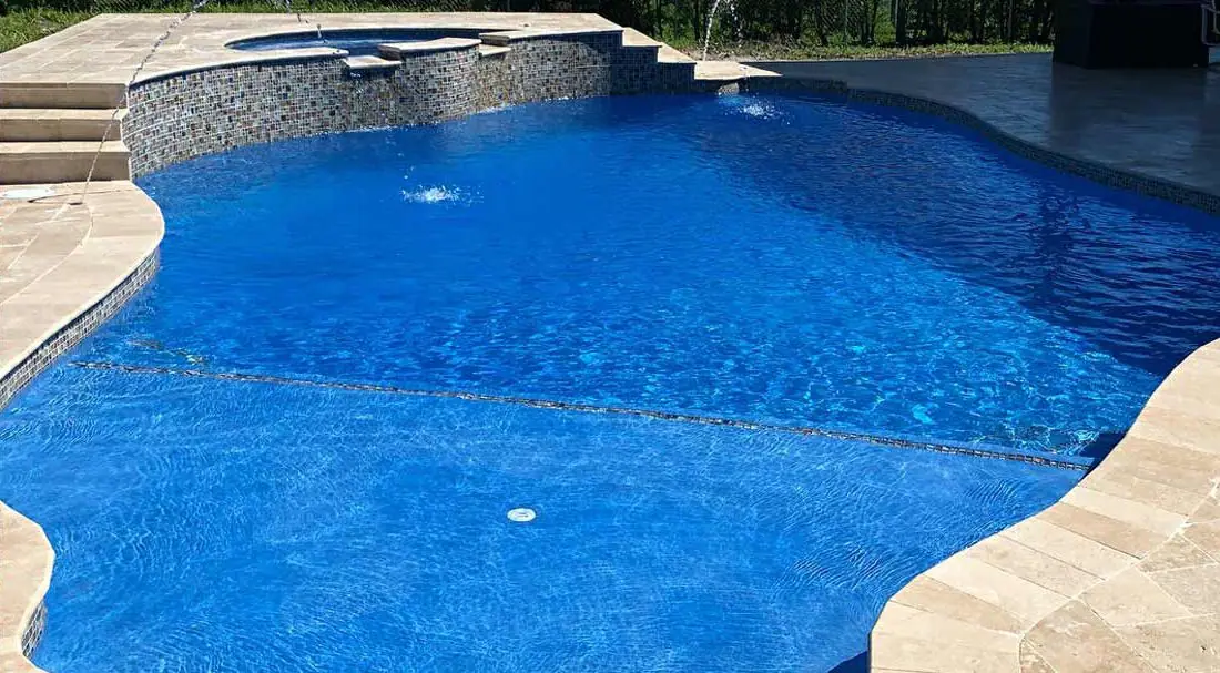 Pool with a Azure glass-bead finish, free-form pool with sun shelf and glass-tile spillway