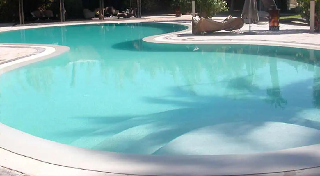 Pool with a Bone glass-bead finish, free-form pool in full sun