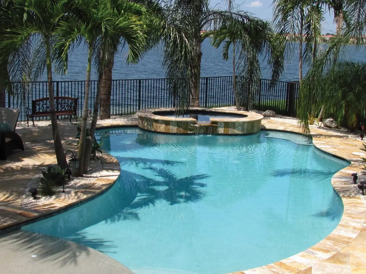 Free-form pool and spa with Aqua Quartz finish by a waterfront