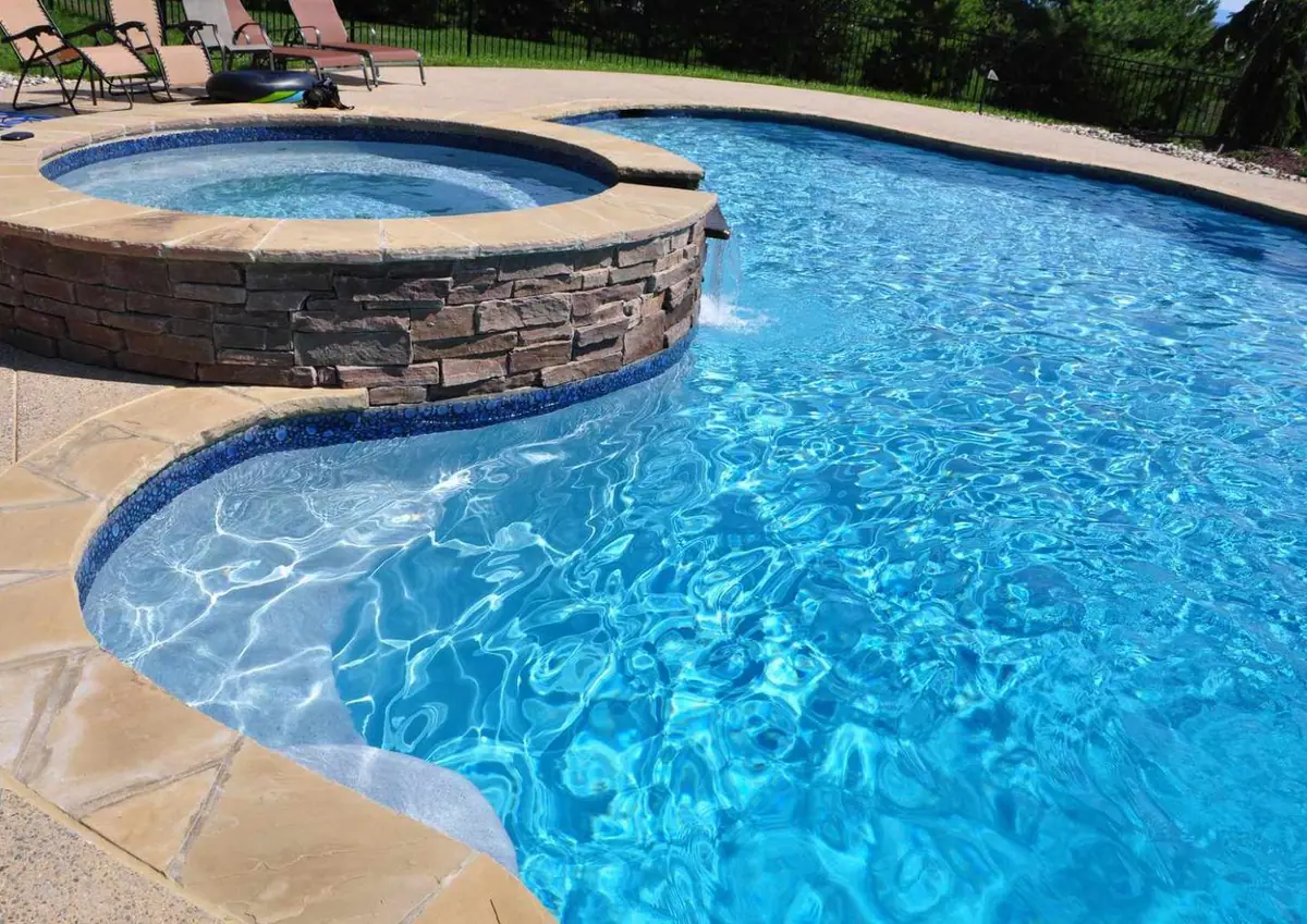 Pool with Super Blue quartz finish beside a raised stone spa