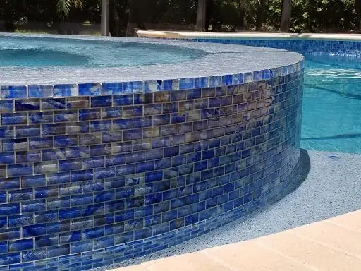 Blue glass waterline tile on a raised spa wall